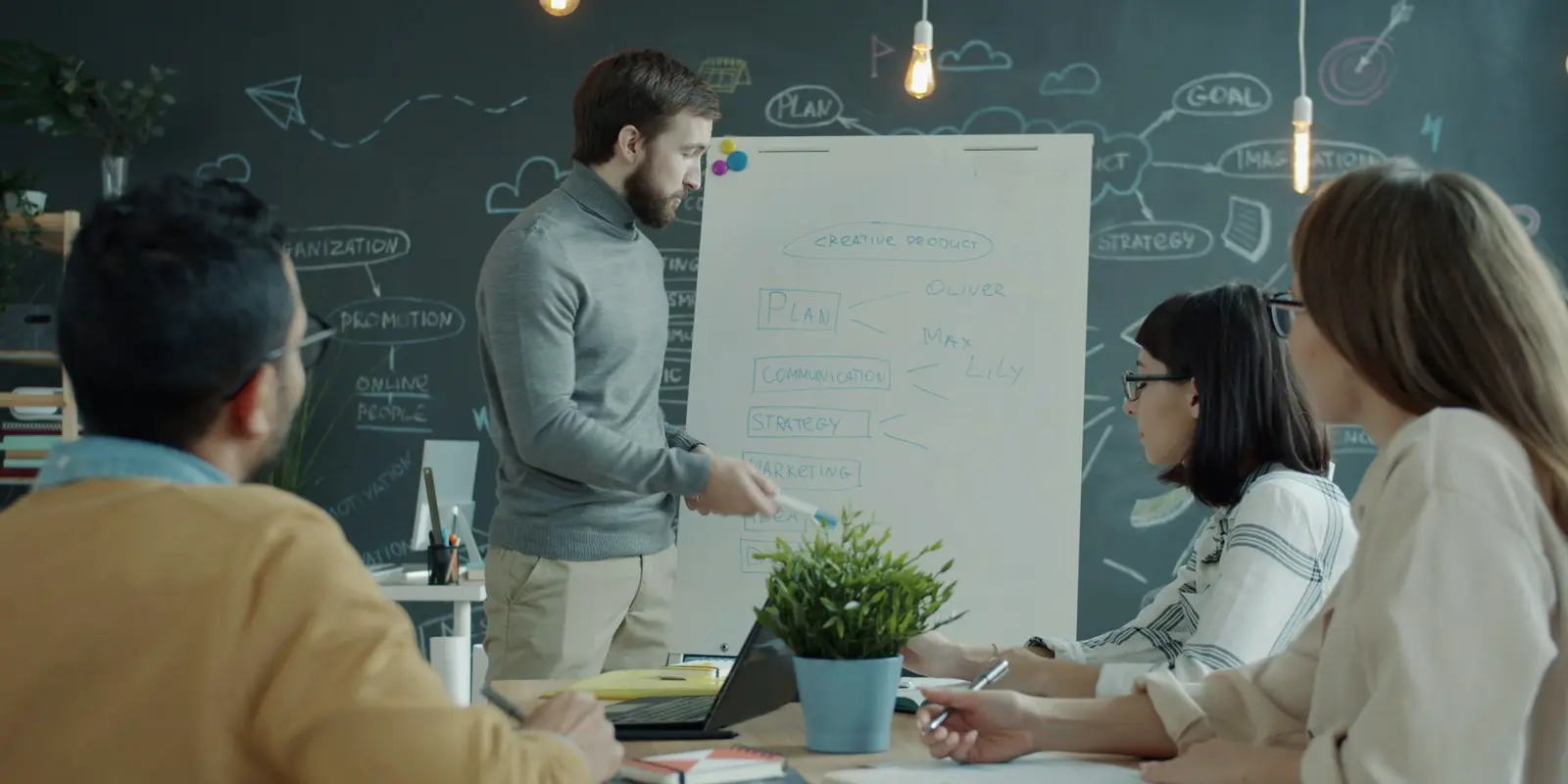 A team listening as a colleague presents at a flip chart